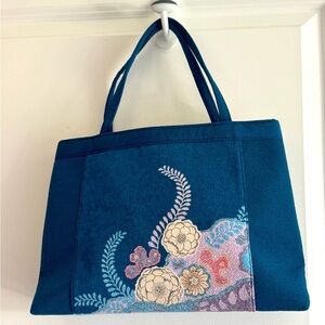 Teal-colored handbag bag featuring intricate floral embroidery